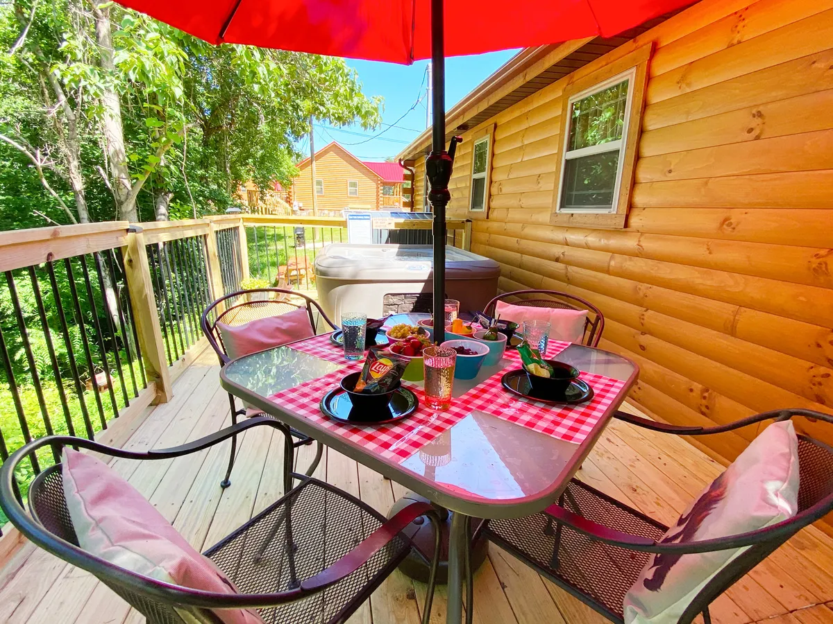 An inviting outdoor table set with food beneath a bright red umbrella, surrounded by lush greenery. The setting suggests an atmosphere perfect for relaxed socializing, outdoor dining, and evening gatherings with friends.